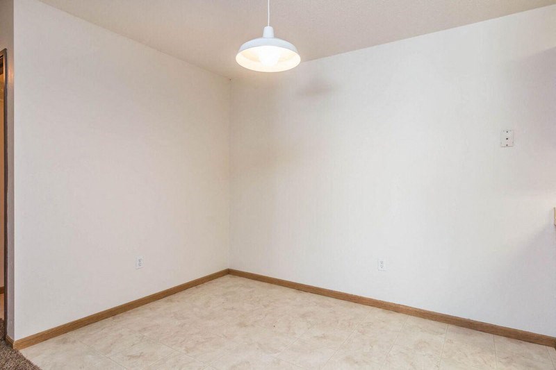 an empty living room with white walls and a ceiling lamp. Fargo, ND Foxtail Townhomes