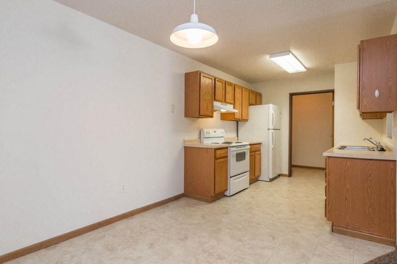 a kitchen with wooden cabinets and a white refrigerator. Fargo, ND Foxtail Townhomes