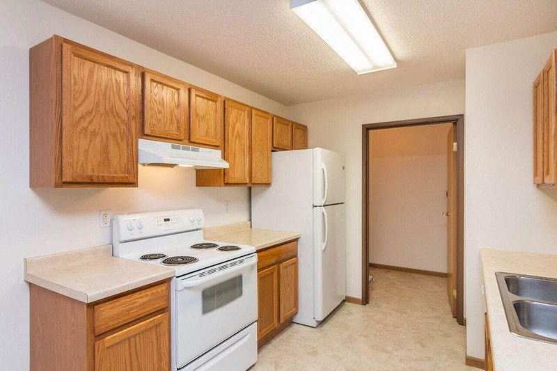 a kitchen with white appliances and wooden cabinets. Fargo, ND Foxtail Townhomes