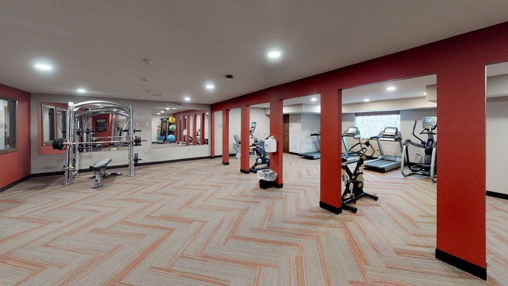 a gym with red walls and a wood floor with exercise equipment