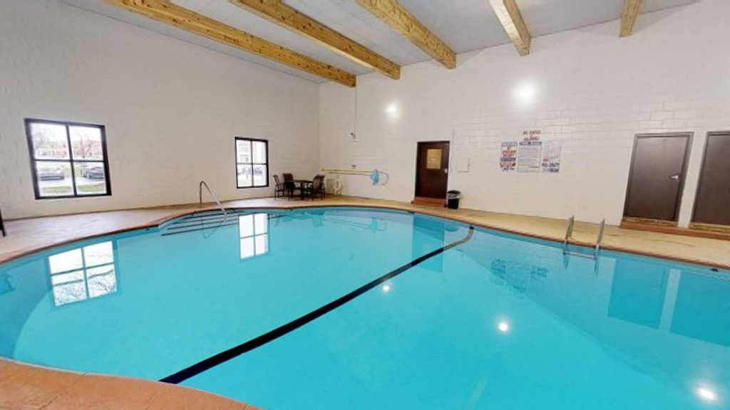 the indoor pool is spacious and has a ceiling with exposed beams