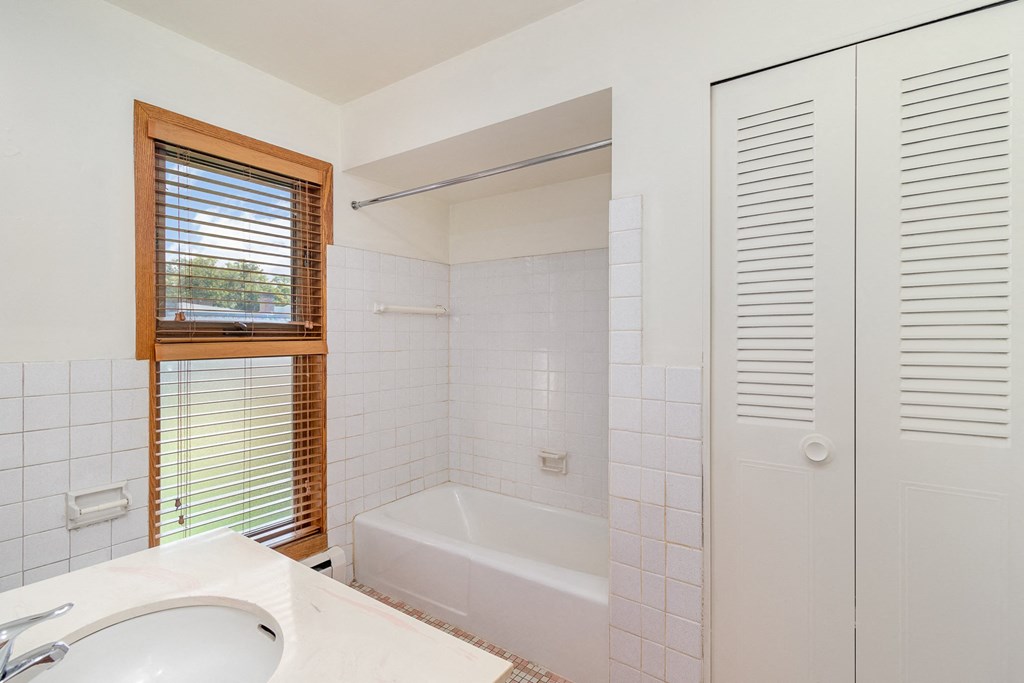 a bathroom with a tub and a sink and a window.  Golden Valley, MN Valley View Apartments