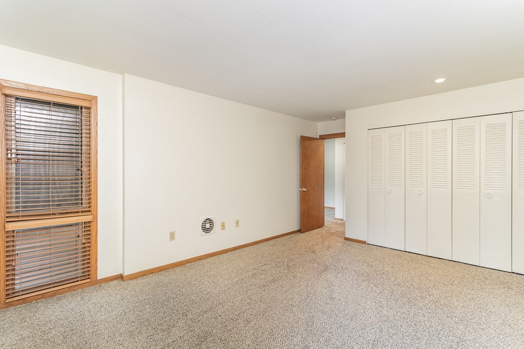 a large room with white walls and a door to a closet.  Golden Valley, MN Valley View Apartments