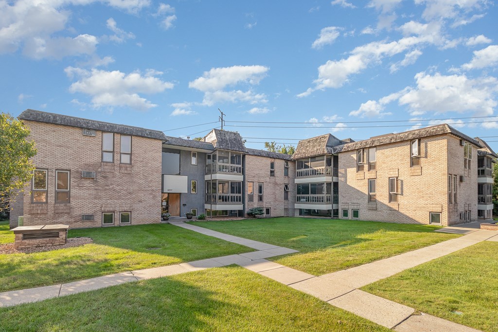 a group of brick apartment buildings with a lawn and sidewalk.  Golden Valley, MN Valley View Apartments