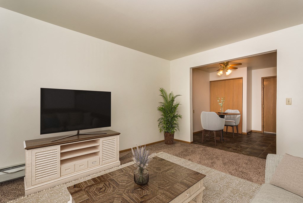 Grand Forks, ND Amberwood Apartments | Living Grand Forks, ND Amberwood Apartments. A living room with a tv and a dining room in the background
