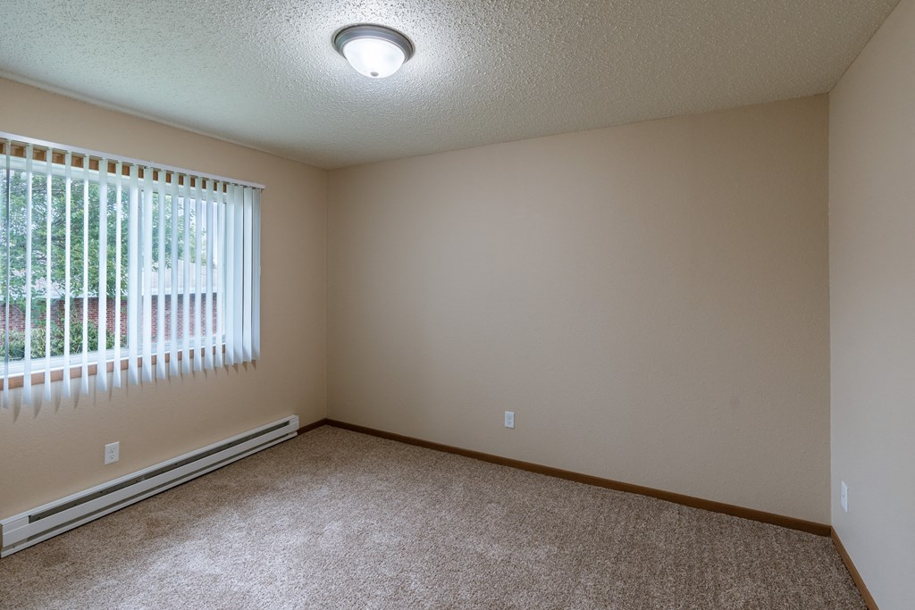 Grand Forks, ND Autumn Apartments. A bedroom with carpeted floors and a window.