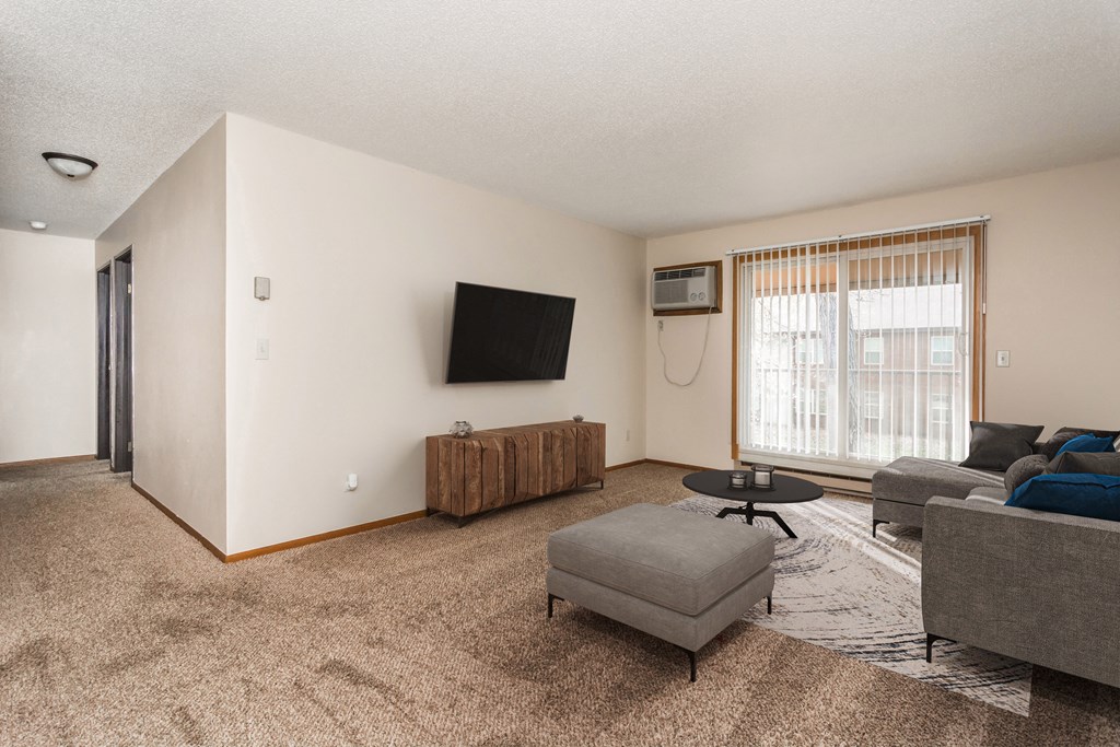 Grand Forks, ND Barrette Arms Apartments.  a living room with a couch and a chair and a tv on the wall
