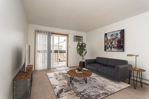 Grand Forks, ND Bristol Park Apartments. a living room with white walls and a sliding glass door leading to a balcony