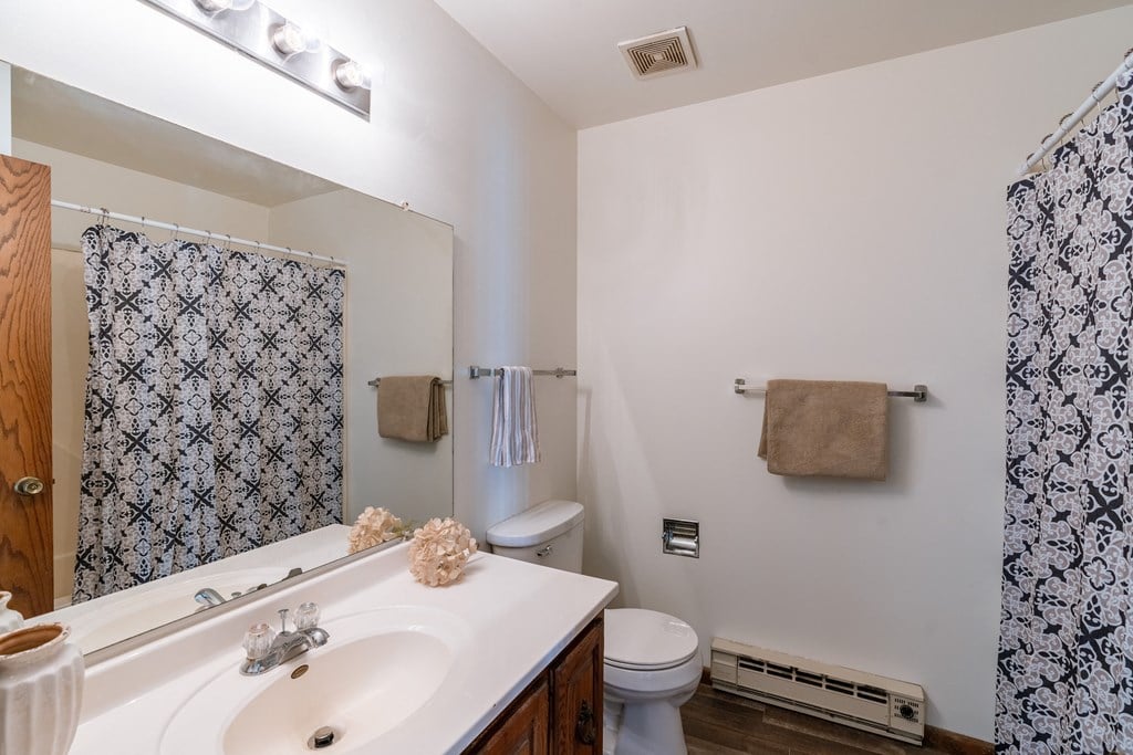 a bathroom with a sink and a toilet and a shower. Grand Forks, ND Cedarwood Apartments