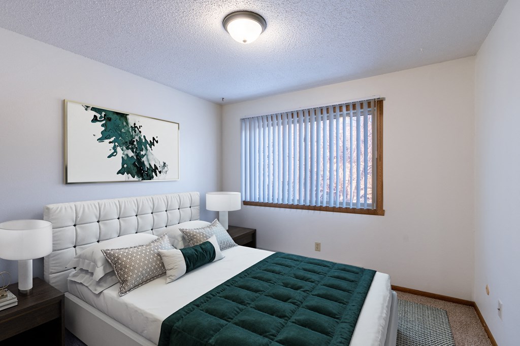 a bedroom with a large bed and a window. Grand Forks, ND Cedarwood Apartments