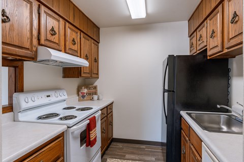 a kitchen with white appliances and wooden cabinets and a black refrigerator