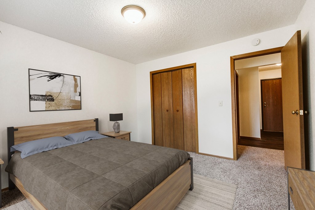 Grand Forks, Chandler 1802 Apartments. a bedroom with a bed and a door to a bathroom