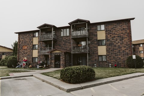 a brick apartment building with balconies and a lawn