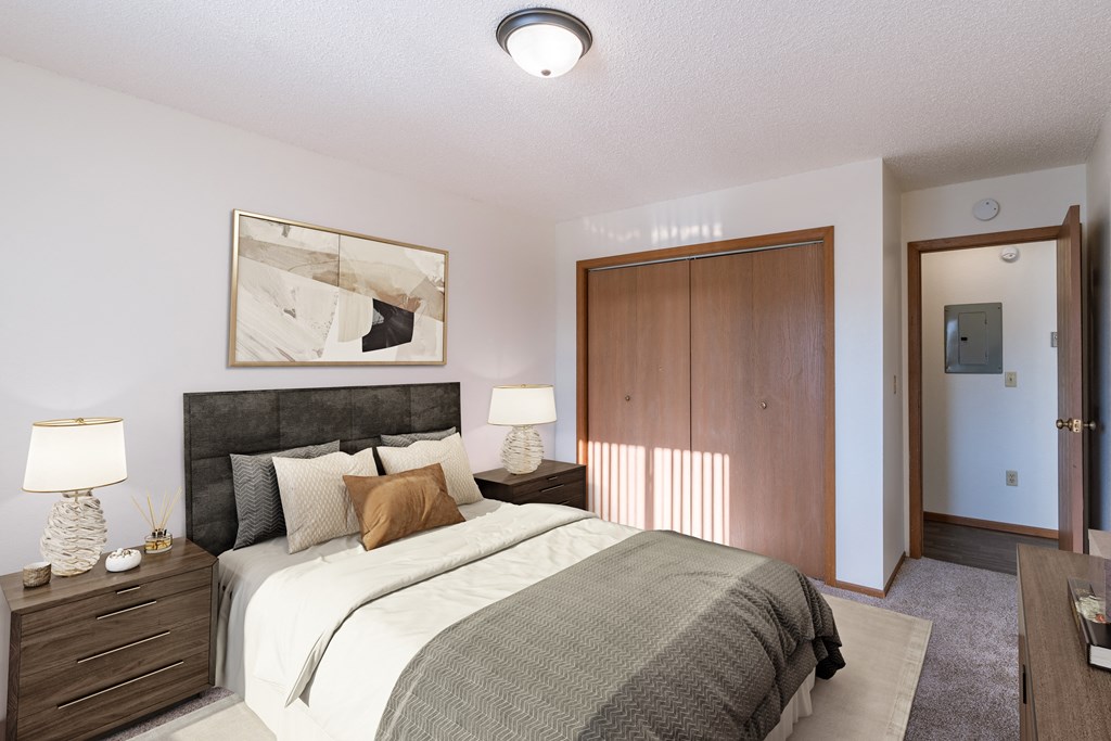 a bedroom with a bed and a closet and a door to a bathroom. Grand Forks, ND Chandler 1898 Apartments