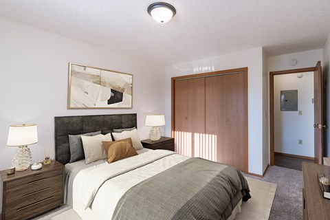 a bedroom with a bed and a closet and a door to a bathroom. Grand Forks, ND Chandler 1866 Apartments