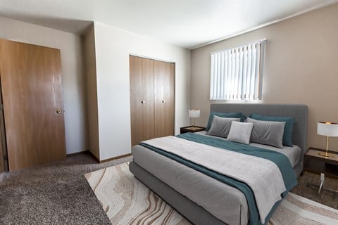 Grand Forks, ND Cherry Creek Apartments. A bedroom with a bed and a wardrobe with a window