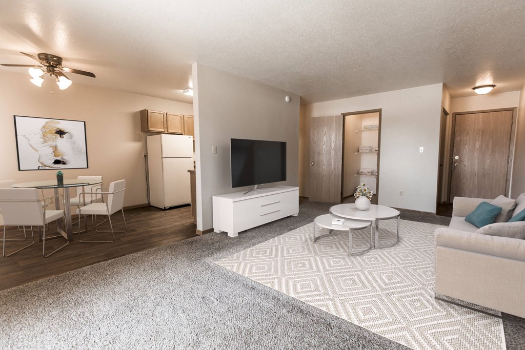 Grand Forks, ND Cherry Creek Apartments a living room with a white rug and white furniture with a dining room in the background
