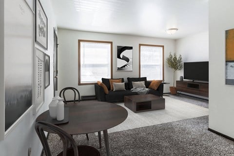 Grand Forks, ND Claremont Apartments. a living room with white walls and grey carpet with two windows. A black couch, 2 chair dining table, coffee table and tv fill the room