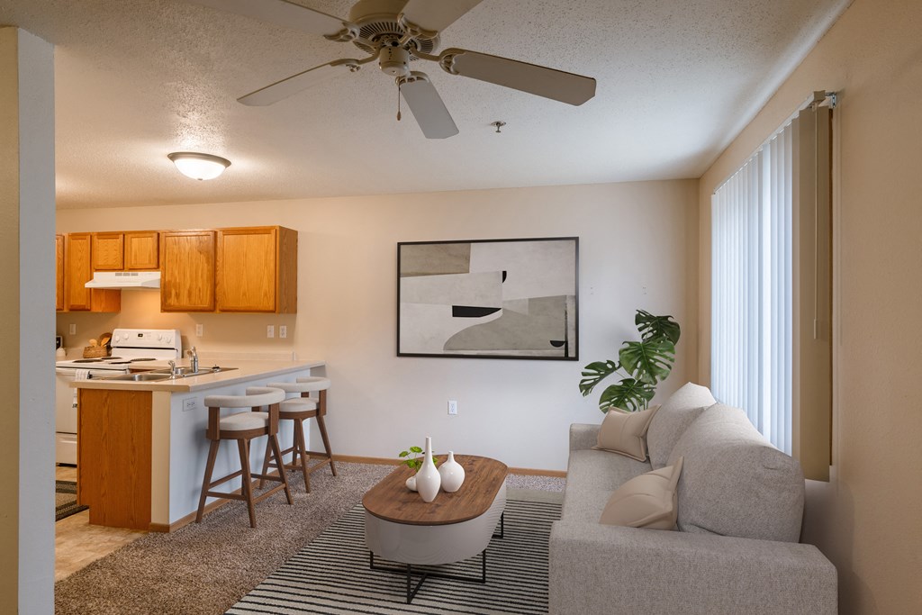 A living room with a couch and a table in front of a kitchen. Grand Forks, ND Creekside Apartments.