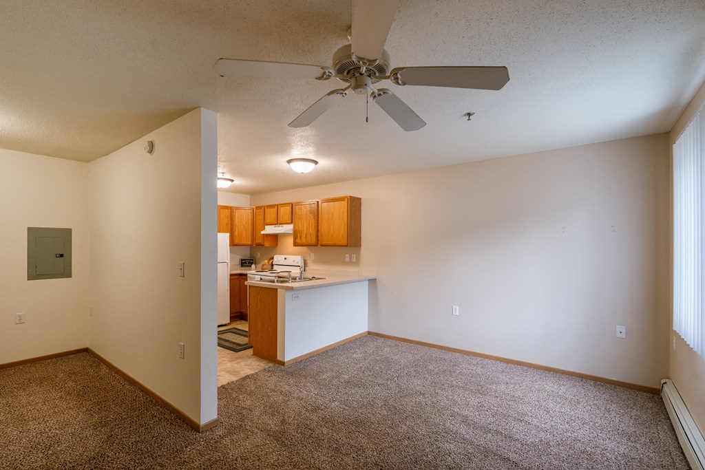 Grand Forks, ND Creekside Apartments. An empty living room with a ceiling fan and a kitchen