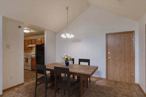 a dining room and kitchen with a wooden table and chairs