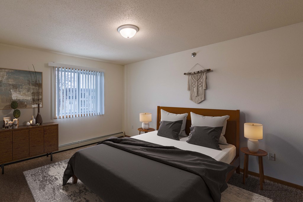 A bedroom with a bed and a dresser and a window. Grand Forks, ND Creekside Apartments.