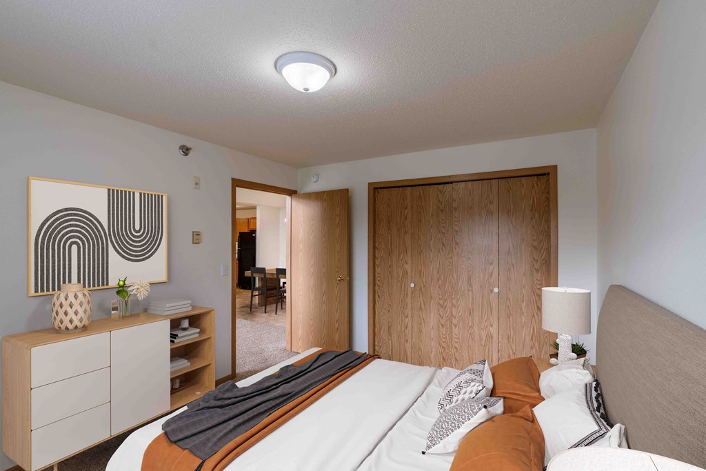 A bedroom with a bed and a closet. Grand Forks, ND Creekside Apartments.