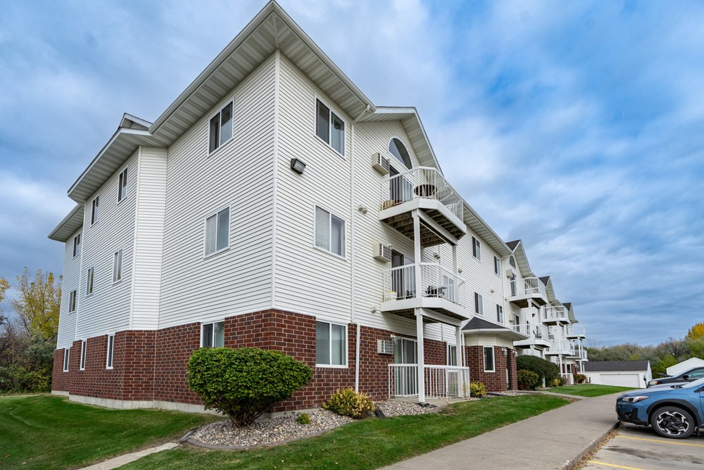 Grand Forks, ND Creekside Apartments | Exterior Grand Forks, ND Creekside Apartments. A white apartment building with a sidewalk in front of it