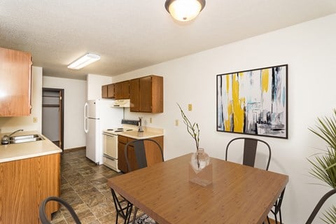 Grand Forks, ND Grandview I Apartments. a kitchen and dining area with a four chair table and art on the wall