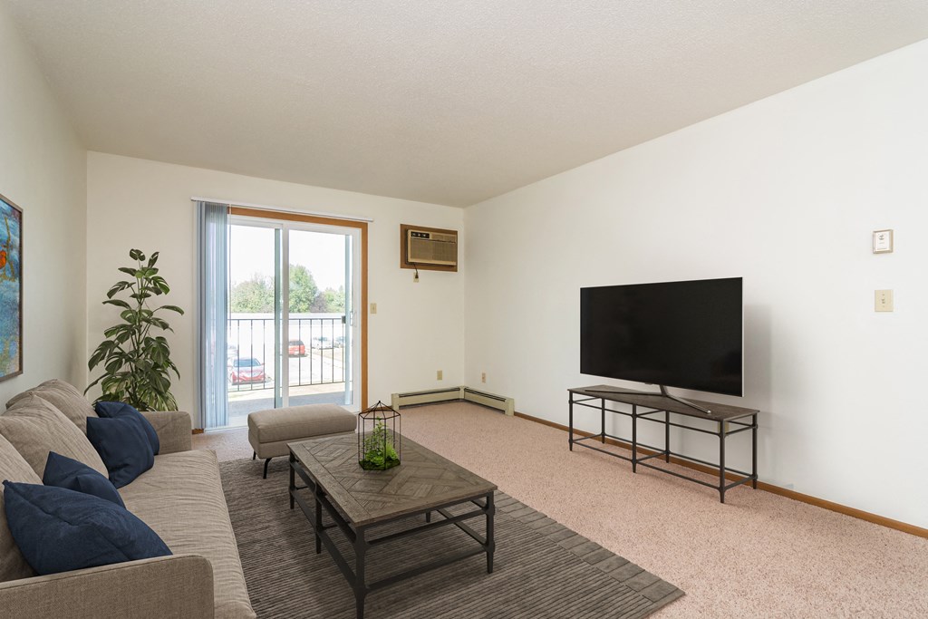 Grand Forks, ND Grandview I Apartments. a living room with white walls and a sliding glass door leading to a balcony