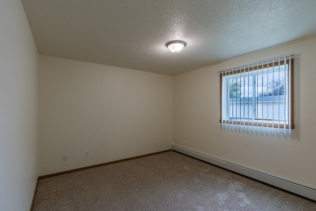 Grand Forks, ND Grandview Apartments. A bedroom with carpeted floors and a window.