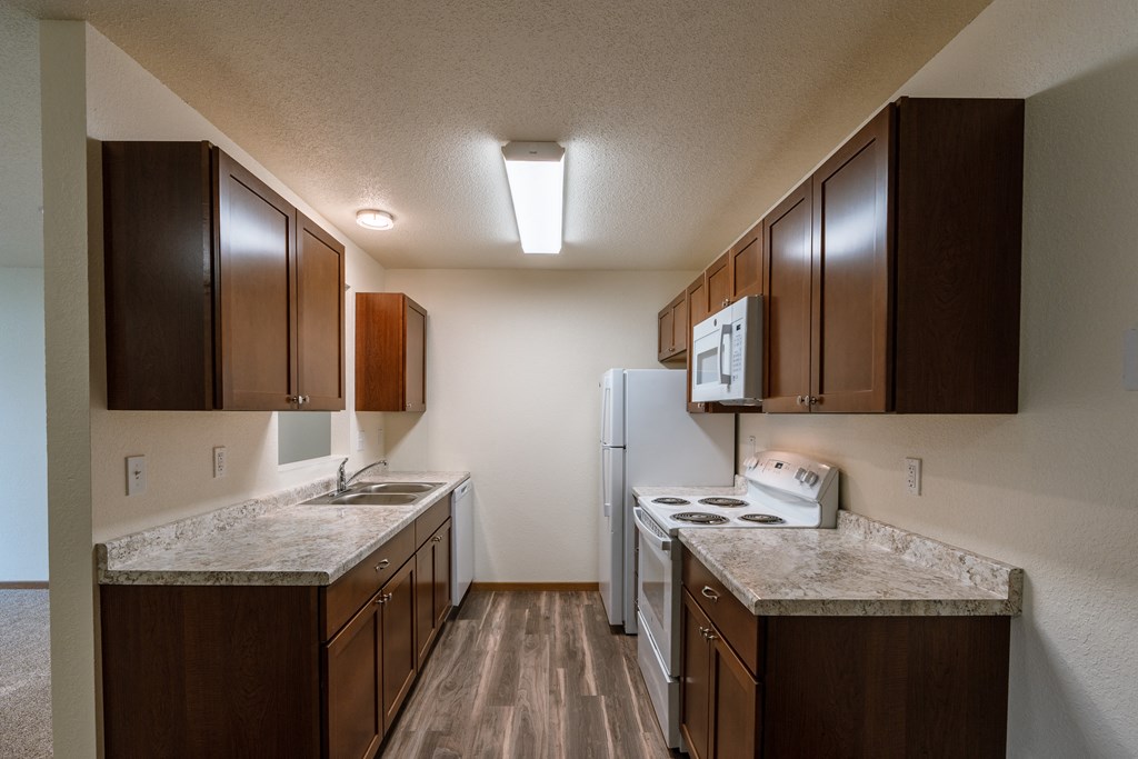 Grand Forks, ND Grandview Apartments. A kitchen with white appliances and wood floors.