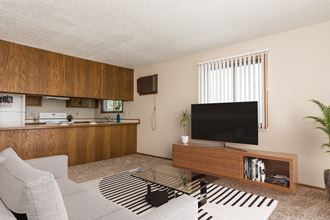 Grand Forks Harrison and Richfield Apartments. A living room with the kitchen with a tv, couch, and coffee table in the background - Photo Gallery 4