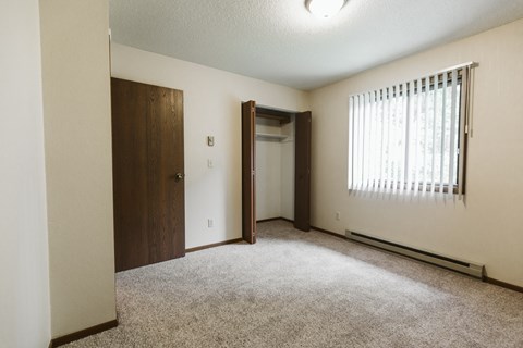 Grand Forks Harrison Apartments. A bedroom with a window and a door to a closet
