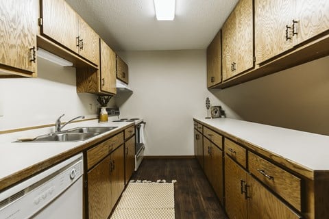Grand Forks Harrison Apartments. kitchen with wooden cabinets and white appliances and a sink