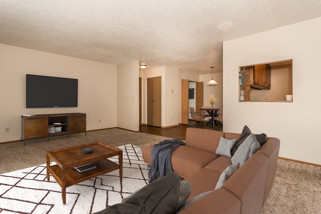 Grand Forks Kremer Apartments  A living room with a couch, coffee table, and tv with a dining area in the background