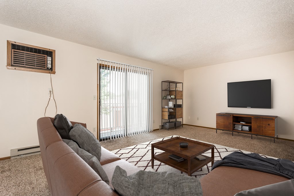 Grand Forks Kremer Apartments. A living room with a couch and a coffee table with a glass sliding door.