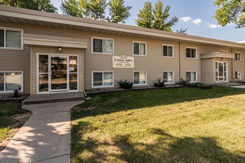 Goldmark's Louise building with a lawn and walkway in front of it