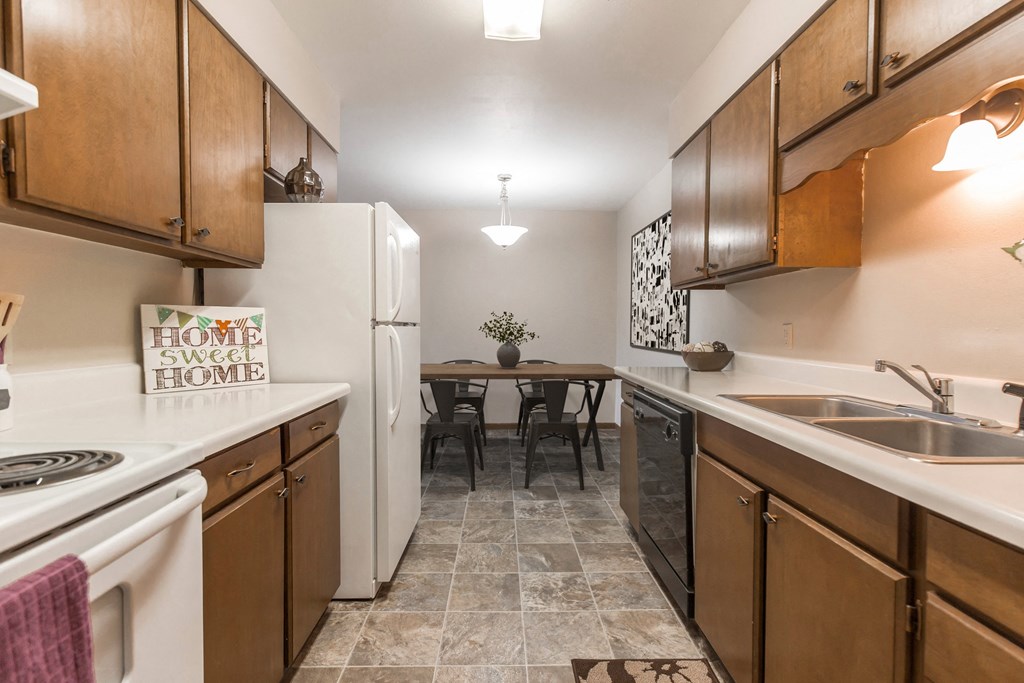 Grand Forks, ND Mayfair Apartments a kitchen with wooden cabinets and white appliances