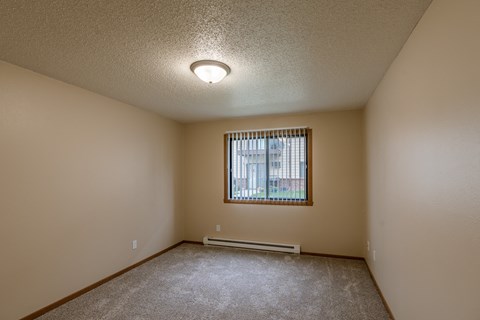 Grand Forks, ND Richfield Apartments. A bedroom with carpeted floors and a window.
