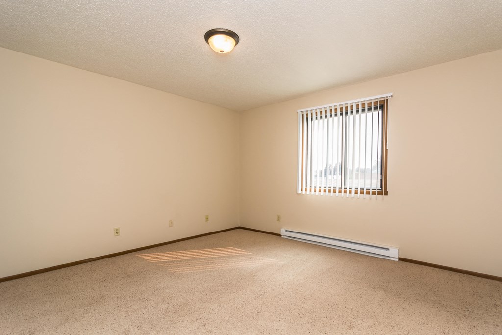 Grand Forks Ridgemont Apartments.  A bedroom with a window and baseboard heater.