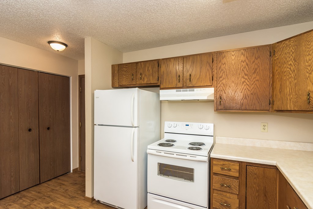 Grand Forks Ridgemont Apartments | Kitchen Grand Forks Ridgemont Apartments. A kitchen with white appliances and a closet in the background.
