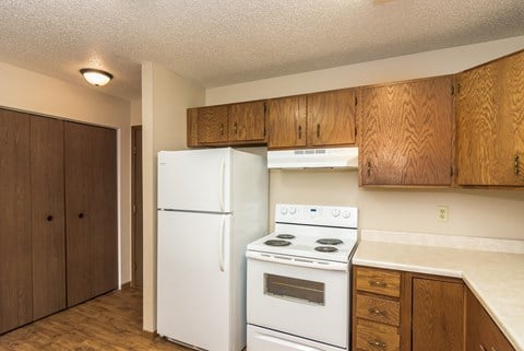 Grand Forks Ridgemont Apartments. A kitchen with white appliances and a closet in the background.