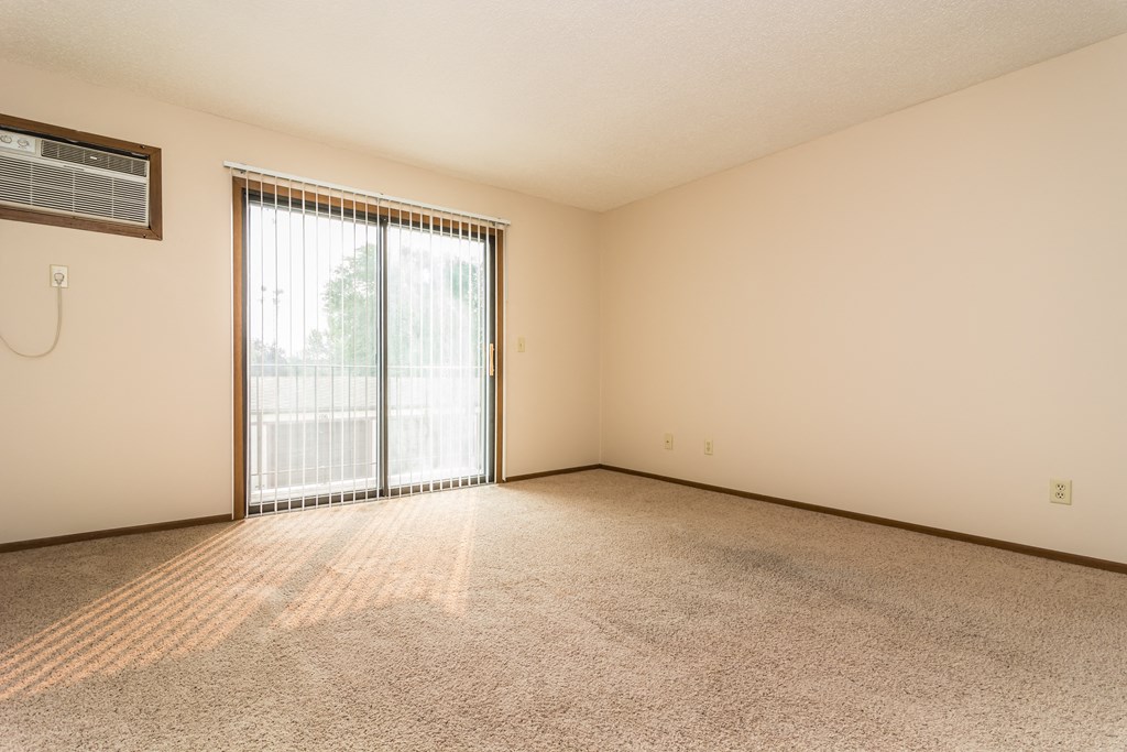 Grand Forks Ridgemont Apartments | Living Grand Forks Ridgemont Apartments. A living room with a glass sliding door and an air conditioner on the wall