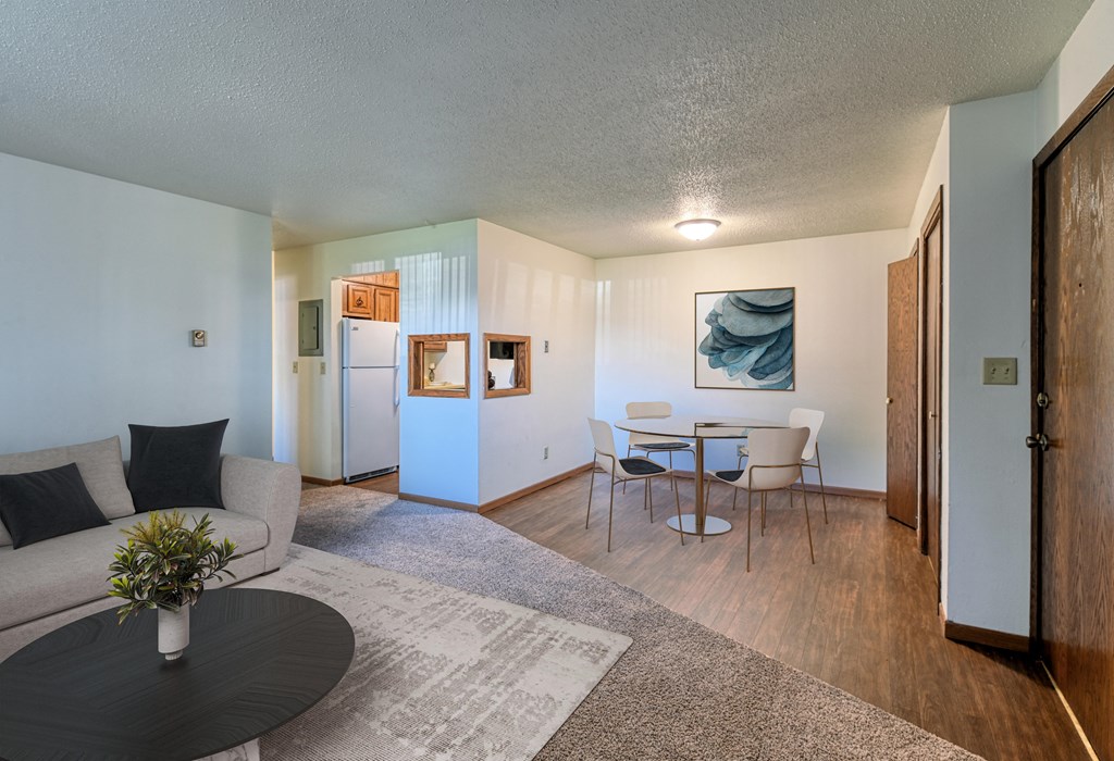 Grand Forks, ND Roughrider Apartments. a living room with a couch table and chairs and a kitchen in the background