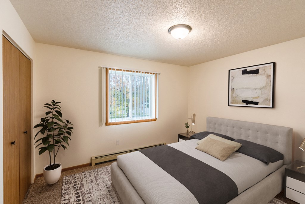 a bedroom with a bed and a potted plant. Grand Forks, ND Southview III Apartments.
