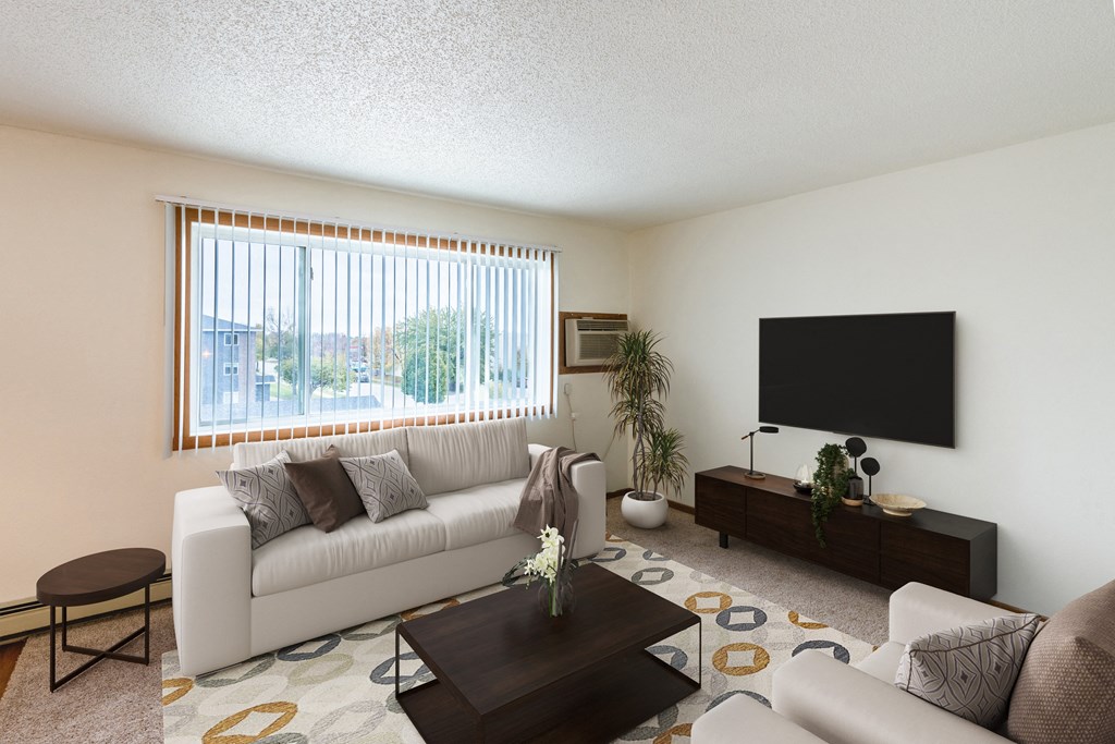A living room of an apartment with a white couch and a television. Grand Forks, ND Southview Apartments.