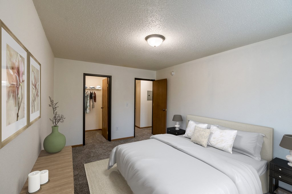A bedroom with a large white bed and a green vase. Grand Forks, ND Southview Apartments.