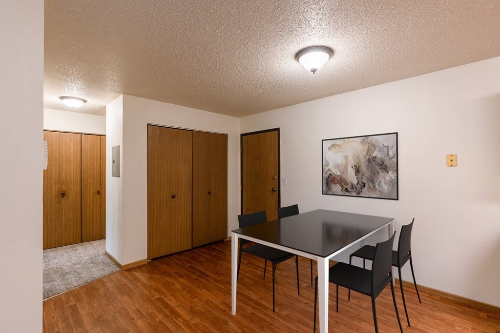 A dining room with a table and chairs and a painting on the wall. Grand Forks, ND Southview Apartments.
