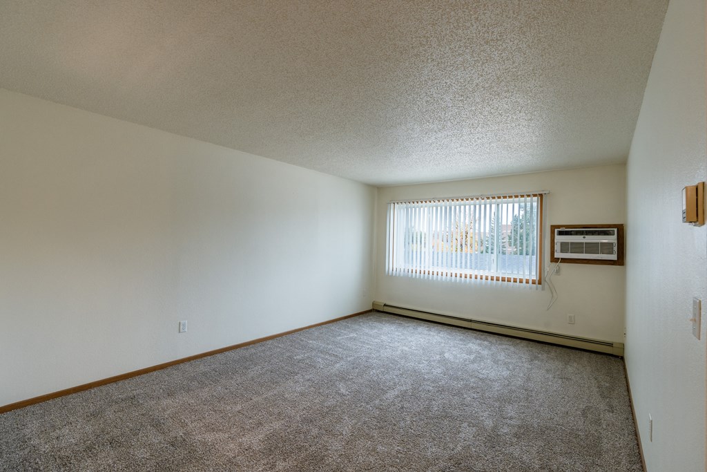 Grand Forks, ND Southview Apartments. A living room with a large window and air conditioning on the wall.